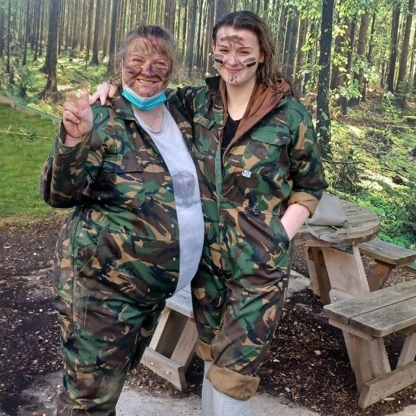 Dee and her granddaughter Tish stand with their arms around each other on their family holiday, dressed in camouflage during a survival experience activity on holiday.