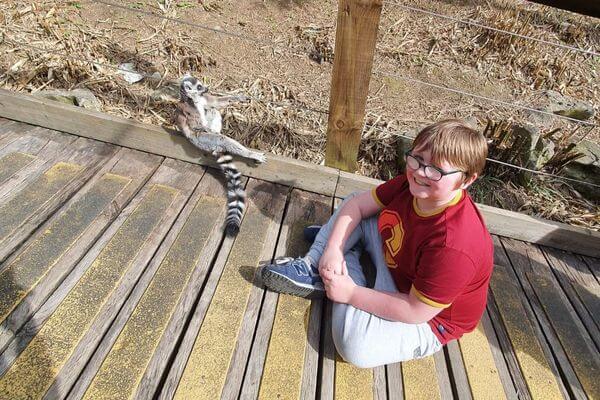 Amy's son, Leon sitting on the floor with a ring-tailed lemur.