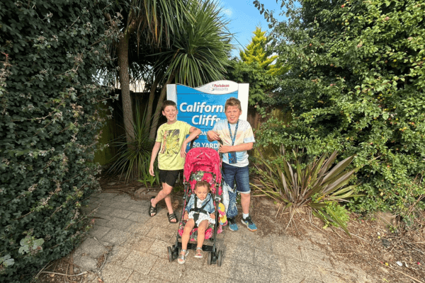 A photo of Jenny's twin and toddler in front of a "California Cliff" sign.