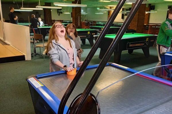 Amelia playing air hockey and smiled happily in the amusement park.