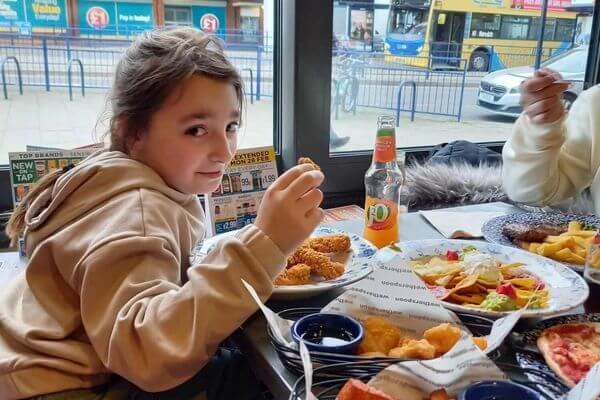 Eden holding a fried chicken leg in her hand at a restaurant