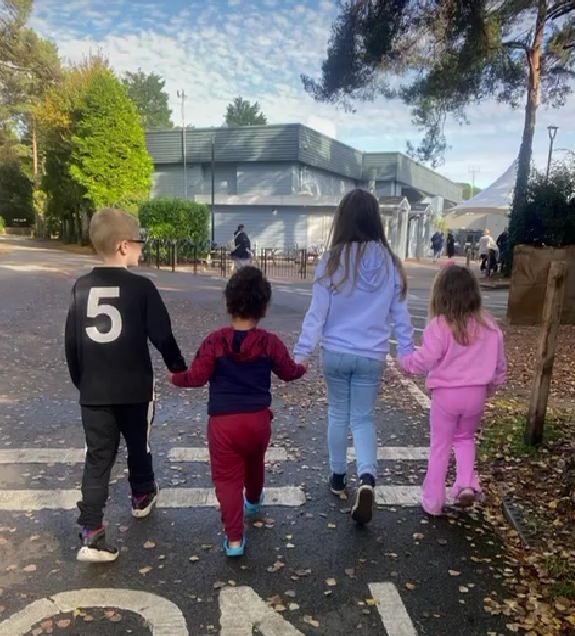 Four children walking holding hands in a caravan park on holiday