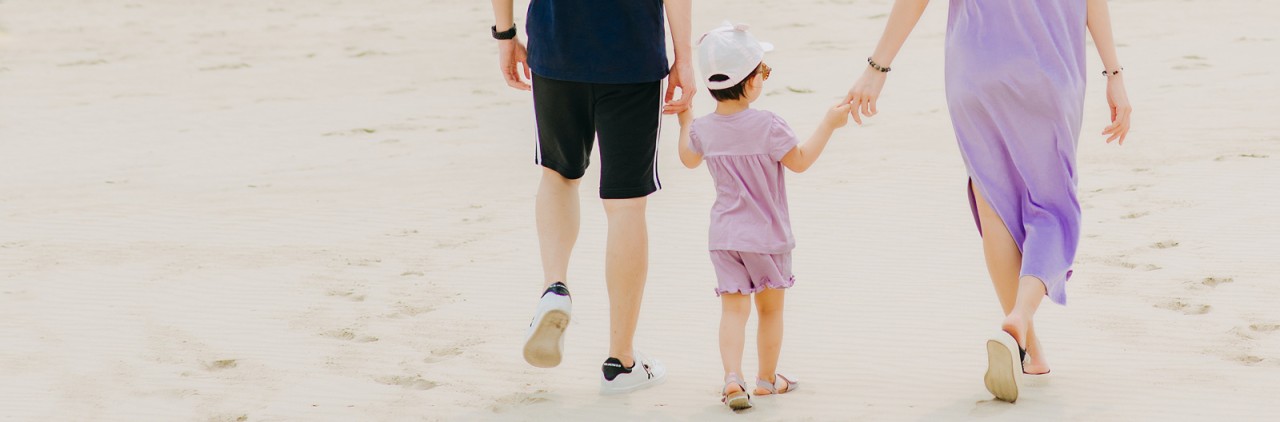 two adults and a small child walking on sand