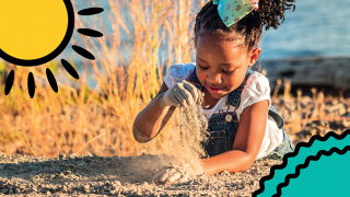 A child plays in the sand on the beach on her first family holiday