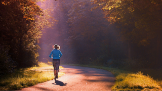 A woman running along a sunlit path