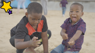 2 boys play with the sand on their family holiday