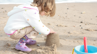 A girl is building a sandcastle on the beach