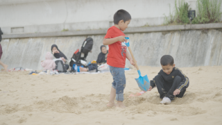 Two boys dig in the sand on their family holiday.