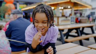 Child eating a marshmallow with a smile on her face
