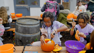 Two children carving pumpkins