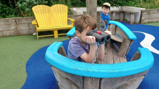 Two boys playing on a wooden play ship 