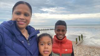 A mother and her children smiling while standing on the beach