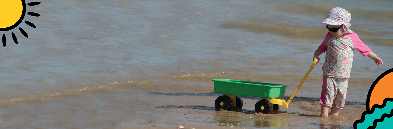 A child pulls a toy trolley along the beach on holiday