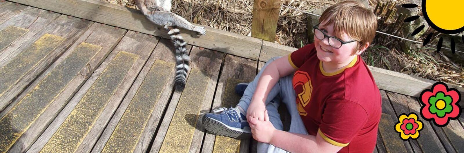 Amy's son, Leon sitting on floor with a ring-tailed lemur next to him