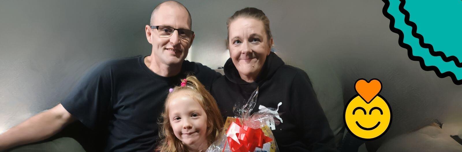 A family photo of mum, Emma, with her partner Scott and daughter Evie-Rose smiling happily.