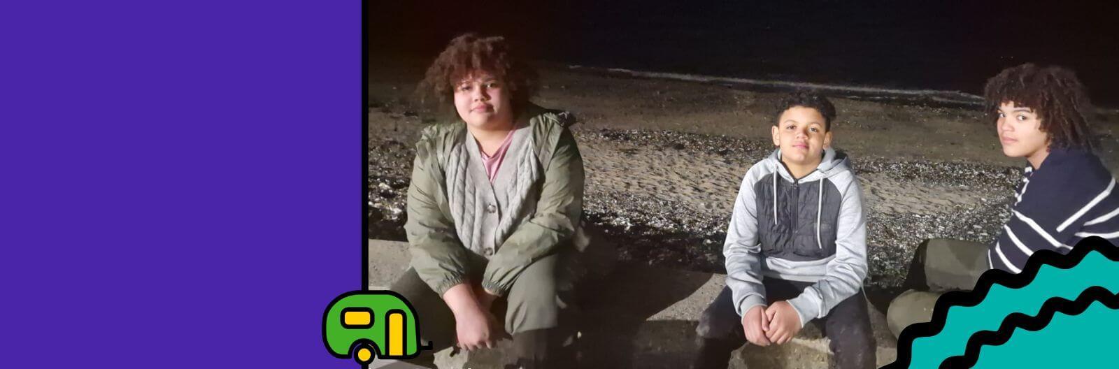 A photo taken by Stacy of her three kids sitting on a bench at the beach after sunset.