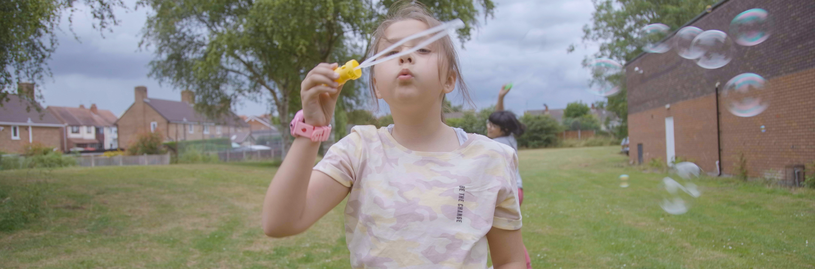 A child blows bubbles in a green park.