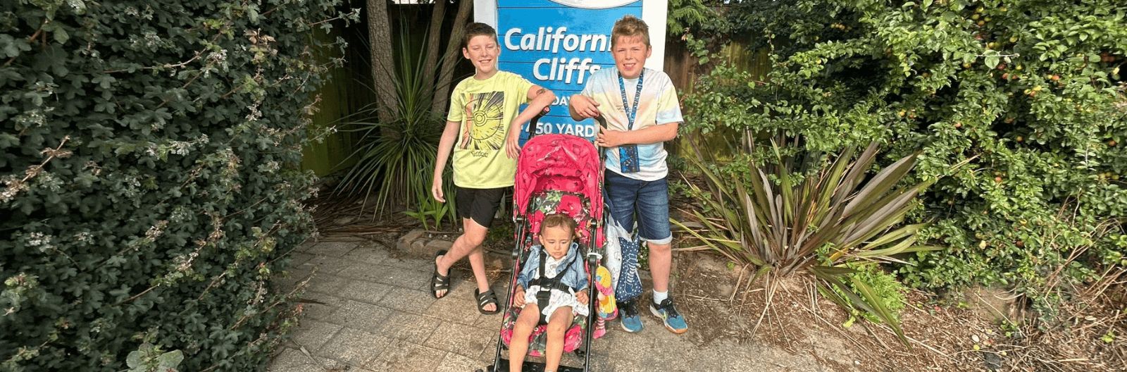 A photo of Jenny's twin and toddler in front of a "California Cliff" sign.