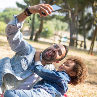 A dad and child are taking a selfie together on a family holiday. They