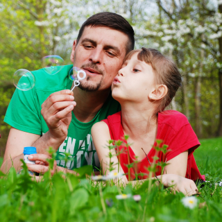 Father and daughter blow bubbles on a summer