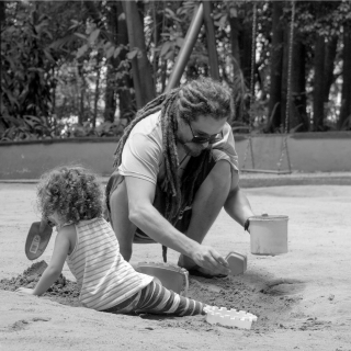 Dad and daughter play in a sandpit at a park on holiday
