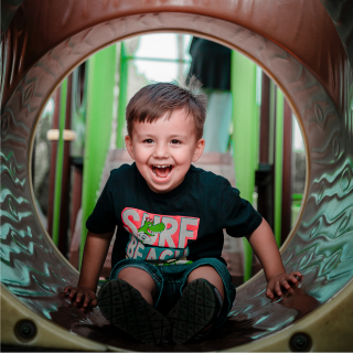 A young child sits inside a slide having fun on holiday.