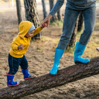 A child and adult in wellies are exploring a local park