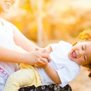 Child sitting on parents lap, leaning back and smiling