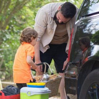 Dad and son pack picnic food into a car