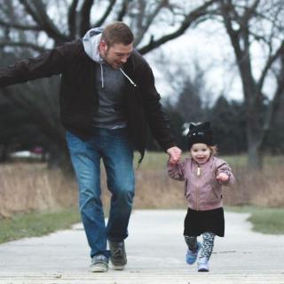 Father and daughter run along a boardwalk