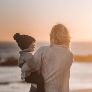 Mum and child hug sunset beach