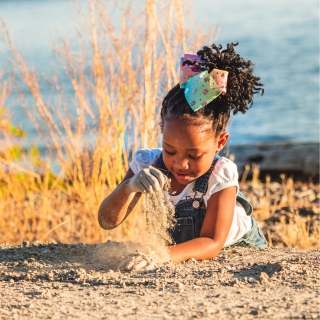 A young girl is playing in the sand on the beach on her family holiday.