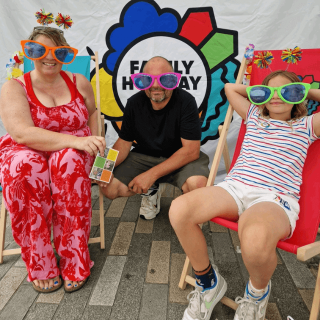 A family of 3 posing inside our pop-up booth in Eastbourne with goofy sunglasses.