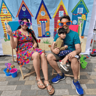 A family of three sitting on the beach chairs with goofy sunglasses.