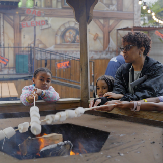 Mum and daughter toast marshmallows over a fire