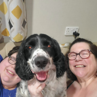 Mum and son smile for a selfie with their spaniel dog sat between them on the sofa.