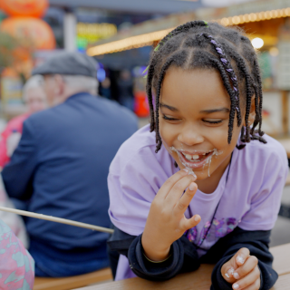 A child is eating a toasted marshmallow on holiday.