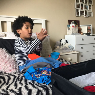 Boy clapping in front of suitcase