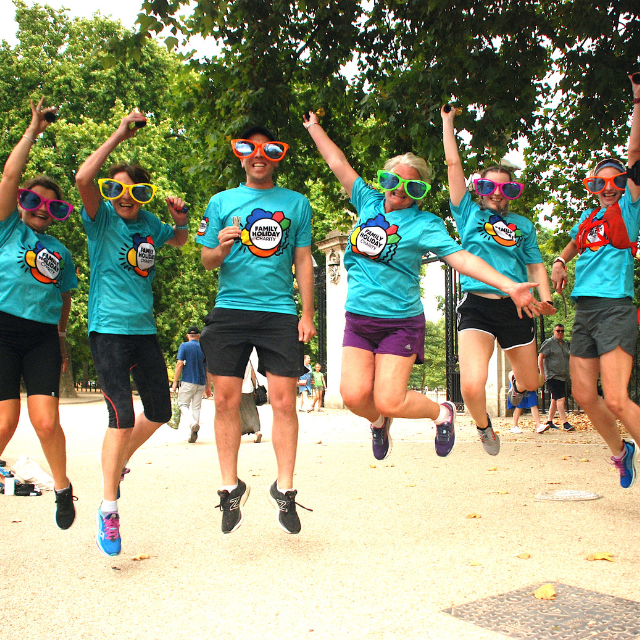 6 people in teal family holiday tshirts jumping for joy and wearing giant sunglasses