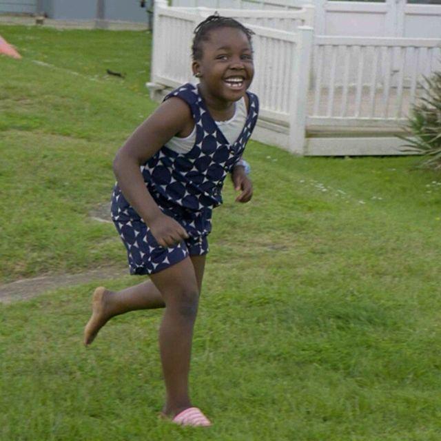 Abi's daughter, Loveina, runs through the green grass of the holiday park with a huge grin on her face on her first family holiday.