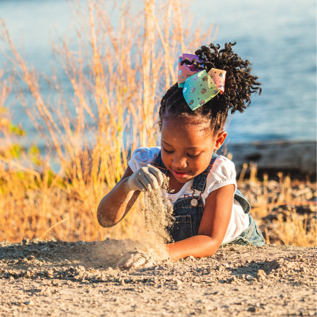 A young girl is playing in the sand on the beach.