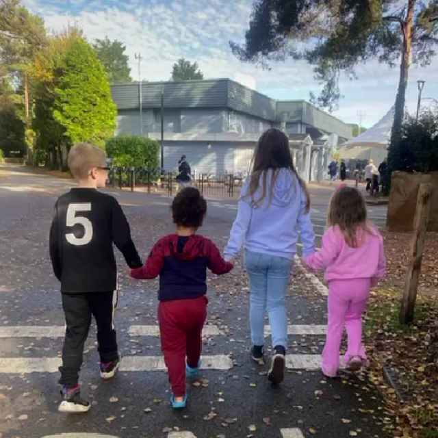 Four children are walking holding hands while on a family holiday in a caravan park