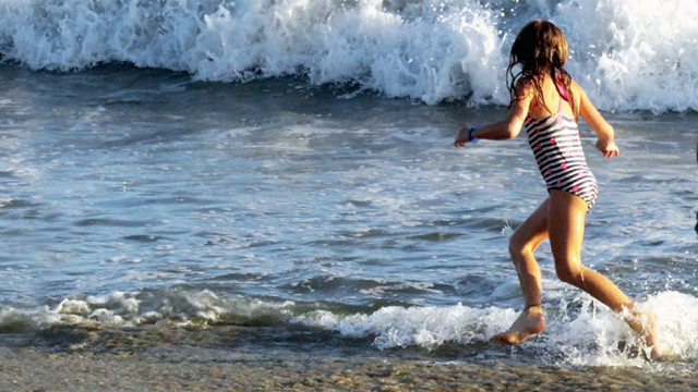 Children run and play in the sea on their family holiday