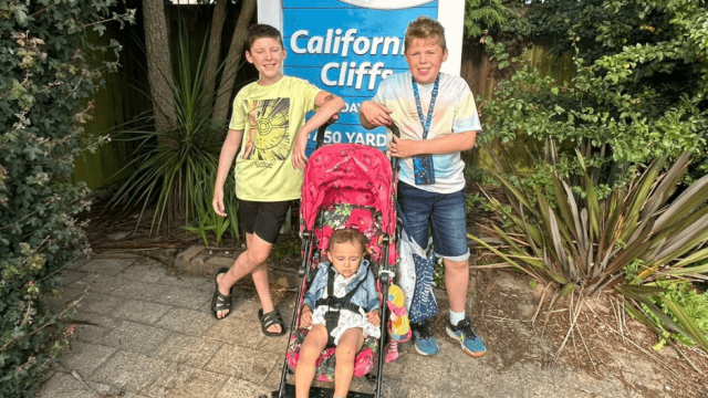 A photo of Jenny's twin and toddler in front of a "California Cliff" sign.